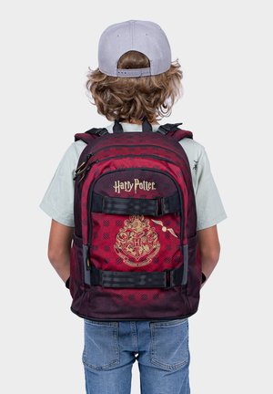 Rot-schwarz karierten Rucksack mit einem goldenen Hogwarts-Wappen, einer vorderen Reißverschlusstasche, gepolsterten Trägern und einem oberen Griff zum Tragen.
