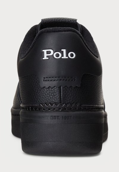 Adidași negri cu un superior din piele texturată, cu cusături contrastante și o talpă din cauciuc. Logo-ul "Polo" este afișat pe călcâi.