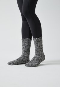 Calcetines de punto con una textura acanalada en blanco y negro; diseño alto que se extiende por encima del tobillo, proporcionando calor y comodidad.