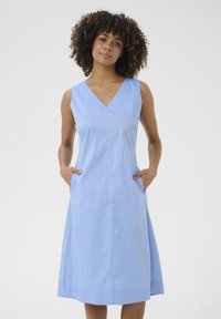 Light blue sleeveless dress with a V-neckline, side pockets, and a knee-length A-line silhouette. Smooth fabric with a subtle texture.