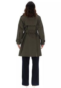 Trench coat verde oliva con vita cintata, spalline e apertura posteriore, caratterizzato da una texture liscia e un design lungo fino al ginocchio.