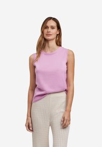 Helles rosa ärmelloses Top aus Strickmaterial mit rundem Halsausschnitt. Kombiniert mit strukturierter, cremefarbener weit geschnittener Hose.