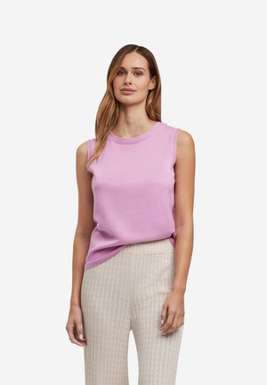 Débardeur sans manches rose clair en maille avec un col rond. Associé à un pantalon large crème texturé.