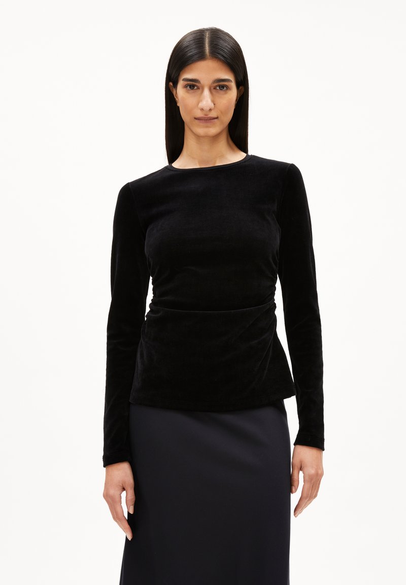 Zwarte fluwelen top met lange mouwen en een ronde hals, met een fitted silhouet en subtiele draperingdetails bij de taille.
