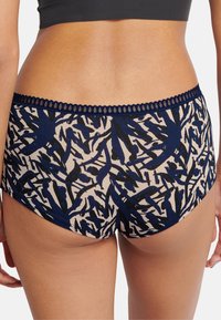 Cotton blend hipster underwear featuring a navy blue and cream abstract bird pattern. Decorative lace waistband adds texture.