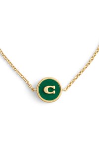 Guldkedja med en rund grön hänge med ett vitt bokstaven 'C' i en polerad yta. Cirkulär design med slät textur.