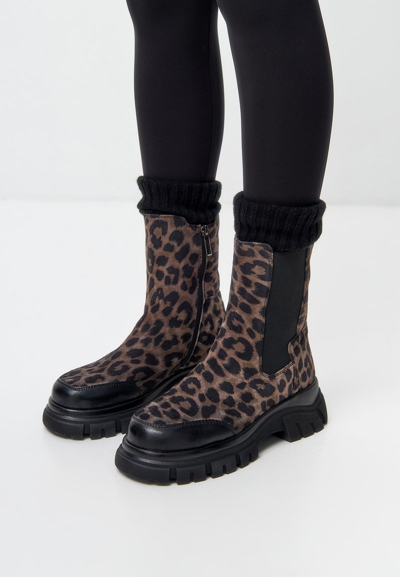 Stivaletti alla caviglia con stampa leopardata, suola in gomma nera, tomaia in tessuto testurizzato, zip laterale e dettaglio in maglia nera sulla parte superiore.