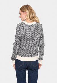 Mustra musterniga mustriga musterniga mustrniga mustrniga, ümar kaelus, soonikkoesed varrukad ja äär, kombineeritud tume siniste teksadega.