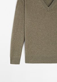 Olivgrüner Strickpullover mit V-Ausschnitt, langen Ärmeln, gerippten Bündchen und Saum. Weiche Textur mit einem dezenten Melange-Muster.