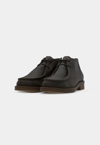 Scarpe in pelle marrone con punte rotonde, dettagli cuciti e una suola in gomma bassa. Presentano una chiusura in pizzo semplice e una texture liscia.