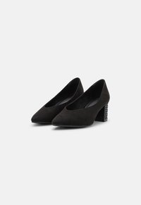 Scarpe nere in suede con tacco alto e punta affilata, dotate di un tacco a blocco testurizzato con un design borchiato. Fodera interna liscia.