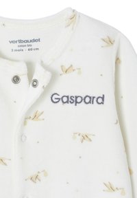 Weißer Fleece-Babyanzug mit Druckknopfverschluss, ausgestattet mit beigen Blatt- und Sternmustern sowie der gestickten Aufschrift "Gaspard" in marineblau.