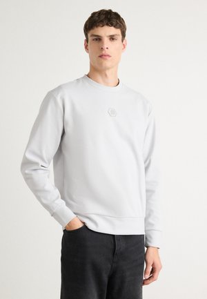 Light gray sweatshirt with a round neckline, long sleeves, ribbed cuffs, and a hexagonal logo detail on the chest. Smooth texture.