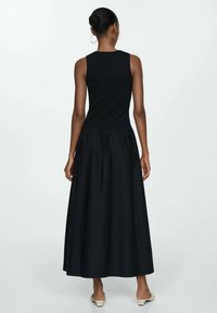 Robe maxi noire avec une coupe sans manches, un corsage ajusté et une taille froncée. Tissu lisse et couleur unie sans motifs ni accents.