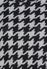 Schwarzer und grauer Stoff mit einem Hexenschachmuster, strukturiert mit einem weichen Strickfinish, das zwischen dunklen und hellen Abschnitten wechselt.