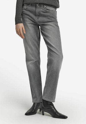 Graue Denim-Jeans mit klassischem geradem Bein, versehen mit fünf Taschen und dezentem Verblassen. Kombiniert mit schwarzen Stiefeletten.