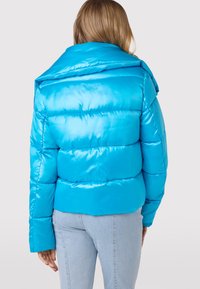 Heldere blauwe pufferjack met een glanzende, gestructureerde afwerking. Bevat een brede kraag, horizontale stiksels en een cropped ontwerp.