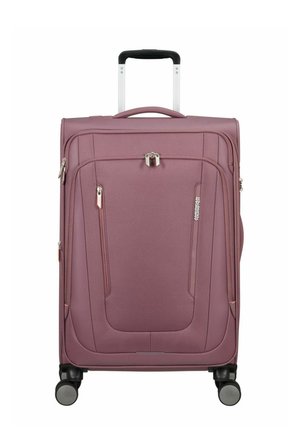 Lila weicher Koffer auf Rädern mit Teleskopgriff, vorderen Reißverschlusstaschen und Schloss, aufrecht stehend vor weißem Hintergrund.