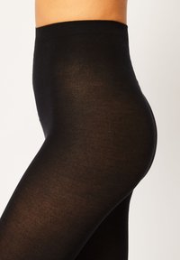Leggings negros elásticos con una textura suave, cintura alta y un diseño ajustado, adecuados para diversas formas de cuerpo.
