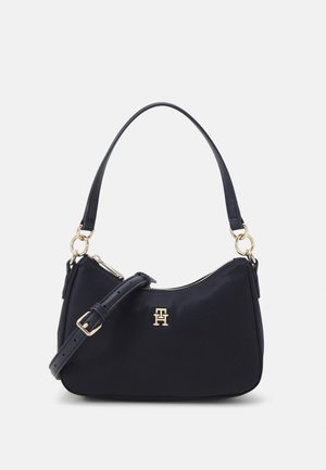 Czarna torba na ramię ze złotymi elementami, regulowanym paskiem, górnym uchwytem i zapięciem na zamek błyskawiczny, z małym złotym logo z przodu.