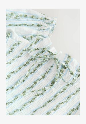 Fehér anyag függőleges kék csíkokkal és zöld virágmintákkal, ráncolt szakaszokkal és a nyakkivágásnál megkötött masnival.