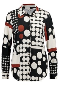 Košile s dlouhým rukávem a knoflíky, pokrytá multibarevnými velkými a malými puntíky v černé, bílé a rezavě červené barvě, uspořádanými do geometrických vzorů.