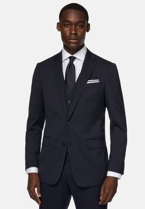 Marineblauer Anzug im Slim-Fit mit einem Zwei-Knopf-Verschluss, Reverskragen und vorderen Taschen. Inklusive hellblauem Hemd und dunkler Krawatte.