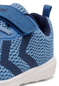 Baskets bleu clair avec une tige en maille, des accents bleu foncé, une sangle Velcro et une semelle blanche texturée. Bout arrondi et col rembourré.