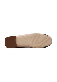 Vahamanskin kumi, jossa on sileä pinta, lievä korko ja tekstuuriset kuviot pitoa varten. Clarks-brändäys näkyvissä.