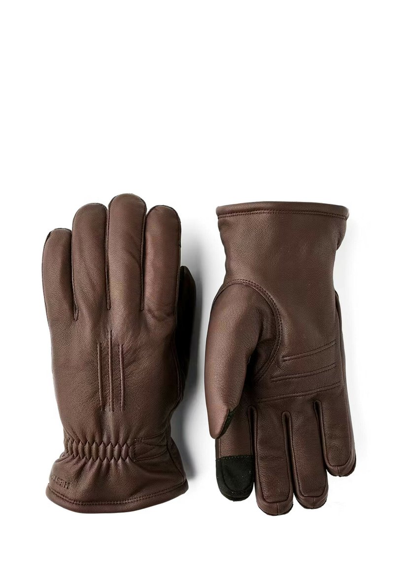 Brune læderhandsker med en glat tekstur, tre sømme på hver finger og en rynket håndled for en tæt pasform. En finger har en sort spids.