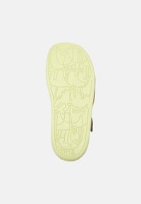 Gul gummisko sula med lekfulla präglingar av djur och abstrakta former, med varumärket "Camper" och storlek "28" angivet.