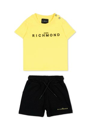 Geel T-shirt met korte mouwen met de tekst "John Richmond" en zwarte short met trekkoord met bijpassend logo op het linkerbeen.