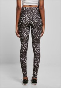 Svarta och vita djurmönstrade leggings med hög midja, med en slät, elastisk tyg och mjuk textur, i kombination med svarta skor.