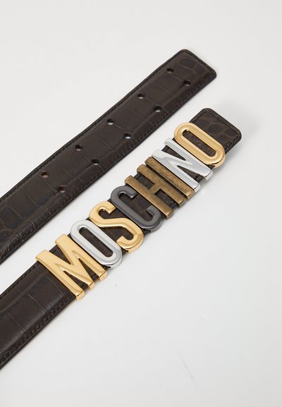 Hnedý kožený opasok s embosovanou krokodílovou textúrou, s odvážnymi kovovými písmenami s nápisom "MOSCHINO" v zlatej, striebornej a čiernej farbe.
