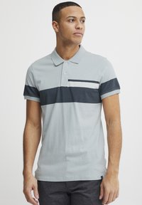 Hele hall päevershirt tumesiniste triipudega, puuvillane materjal, lühikesed varrukad, kolme nööbi klapp ja kitsas lõige.
