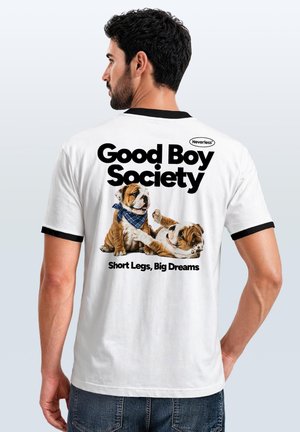 Man wearing a white T-shirt with black trim showing two bulldog puppies and text "Good Boy Society, Short Legs, Big Dreams" on the back.