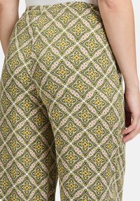 Patronenbroek met een groen, geel en roze geometrisch ontwerp, gemaakt van lichtgewicht stof met een elastische tailleband en zijzakken.