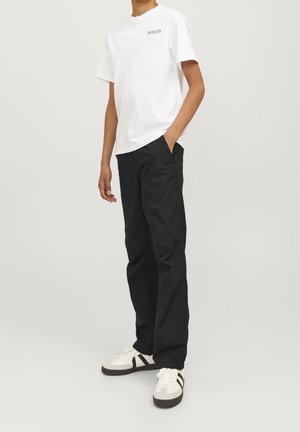 Hvid bomulds t-shirt med et logo på brystet, parret med sorte bukser og hvide sneakers med sorte accenter og strukturerede såler.