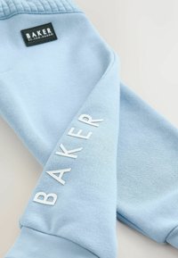 Lysblå sweatpants i et tekstureret, blødt stof. Har et sort mærke med "BAKER" i hvid skrift langs siden.