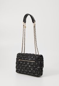 Czarna torebka z cekinami o pikowanej fakturze, wyposażona w złoty łańcuszek jako pasek oraz przednią kieszeń na zamek. Kompaktowy, prostokątny kształt.