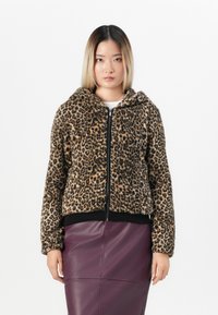 Leopard print zip-up jacket with a soft, textured fabric, hood, and ribbed black cuffs; paired with a purple leather skirt.