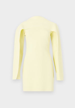 Oblekica bledo rumene barve z odkritimi rameni, dolgimi širokimi rokavi in oprijeto silhueto na enobarvnem ozadju.