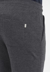 Pantalon de survêtement en coton gris avec une taille côtelée, comportant une poche arrière et une petite étiquette "BLEND" sur le côté.