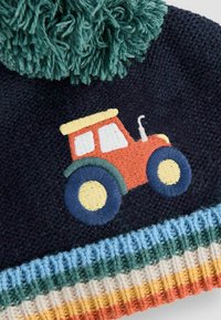 Czapka dzianinowa w ciemnoniebieskim kolorze z zielonym pomponem. Posiada haftowany czerwony traktor z kolorowymi kołami. Rybkowany brzeg w wielu kolorach.