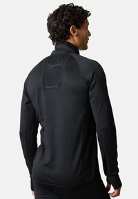 Zwarte lange mouwen sporttop van textuurstof, met een hoge kraag en een logo op de rug. Slank model met strakke boorden en naden.