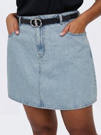 Falda vaquera azul claro con bolsillos delanteros y un cinturón negro con una hebilla doble de anillo plateado, llevada con las manos en los bolsillos.
