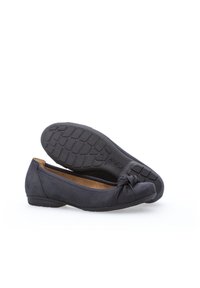 Ballerines en suède noir avec un accent noué sur le bout, semelle en caoutchouc plate avec un motif de grip texturé et doublure intérieure rembourrée.