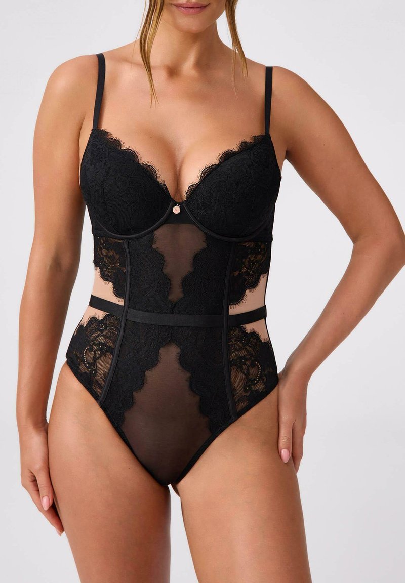 Czarne koronkowe body z przezroczystymi panelami i falistymi krawędziami, z regulowanymi ramiączkami i małym metalowym akcentem na środku przodu.