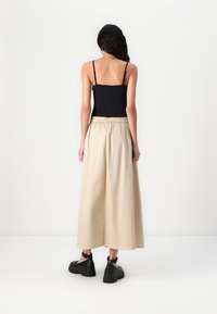 Svart spaghetti strap topp, beige vide bukser med elastisk waist, og svarte platform sandaler. Glatt stoff og løs passform.