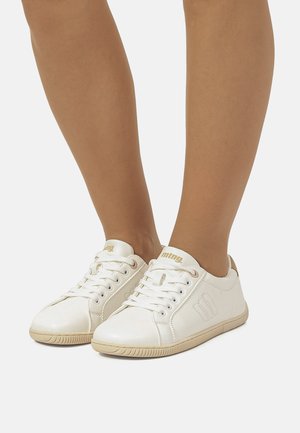 Zapatillas sintéticas blancas con diseño de cordones, acentos en beige y suela de goma texturizada. Presentan un detalle de logo y superficie lisa.